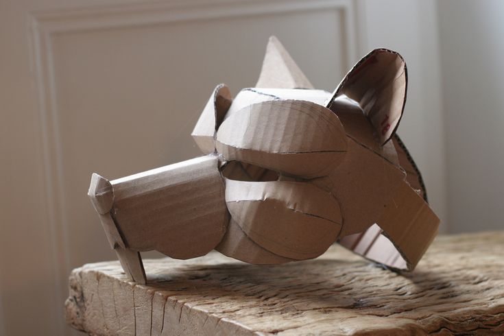 an origami dog made out of cardboard sitting on top of a piece of wood