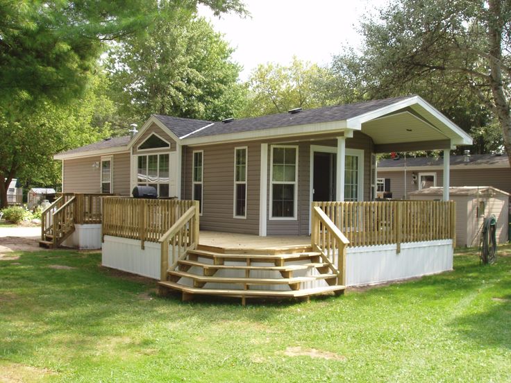 a small house with steps leading up to the front door and covered porch in grass