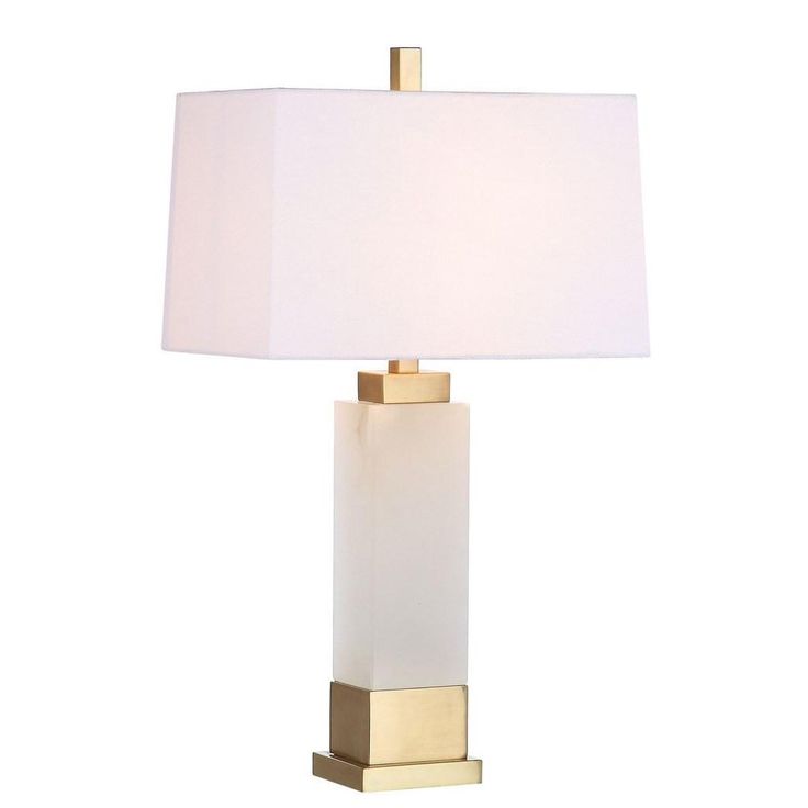 a table lamp with a white shade on the base and a gold frame around it