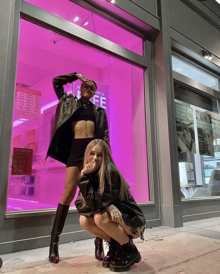 two women are posing in front of a store window with their legs on the ground