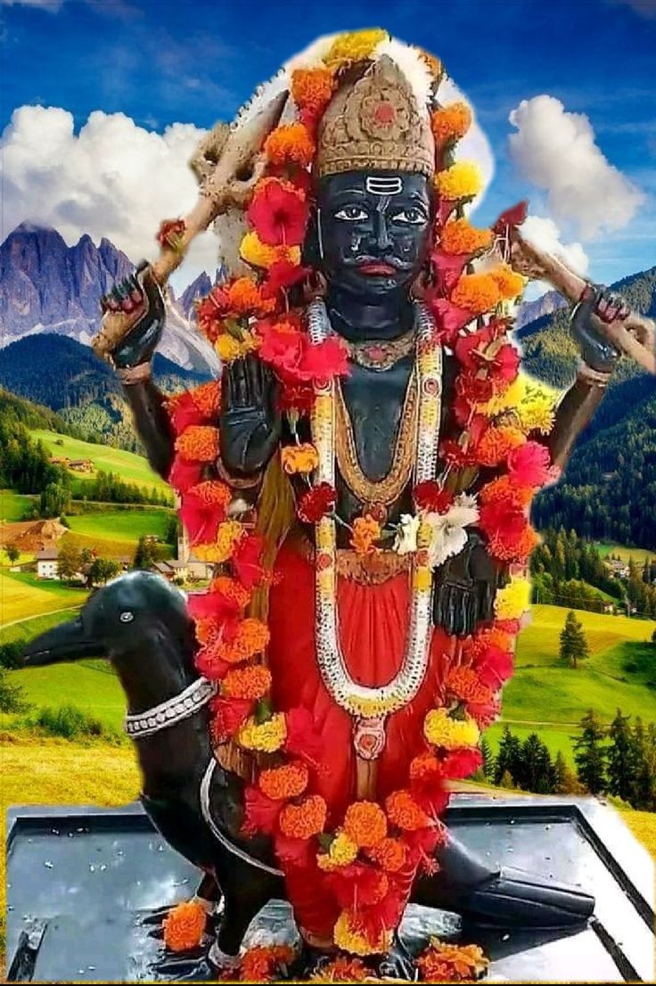 a statue of the hindu god person with flowers around his neck and arms, standing in front of mountains