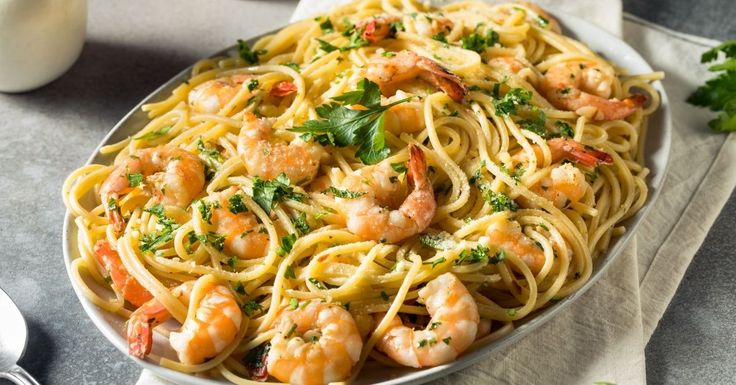 a plate of pasta with shrimp and parsley