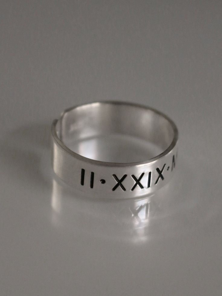 This Roman numeral ring is the perfect piece of personalized jewelry for anniversaries, promise rings and more. Crafted from quality materials, this date ring can be inscribed with custom Roman numerals for a unique piece of jewelry. A great gift for your loved one to commemorate a special occasion. Product Details: Materials: Aluminum, Sterling Silver, Fine Silver, 14k Gold Filled Color: Silver, Gold, Rose Gold Size: 6mm You will receive one hand-stamped ring filled with no enamel finish. Minimalist Hand Stamped Rings For Anniversary, Modern Adjustable Initial Ring For Anniversary, Minimalist Hand Stamped Engraved Ring For Anniversary, Adjustable Initial Ring With Name For Anniversary, Adjustable Engraved Initial Ring For Anniversary, Hand Stamped Ring For Anniversary, Round Band Jewelry With Hallmarks For Anniversary, Modern Jewelry With Hallmarks For Anniversary, Minimalist Jewelry With Hallmarks For Anniversary