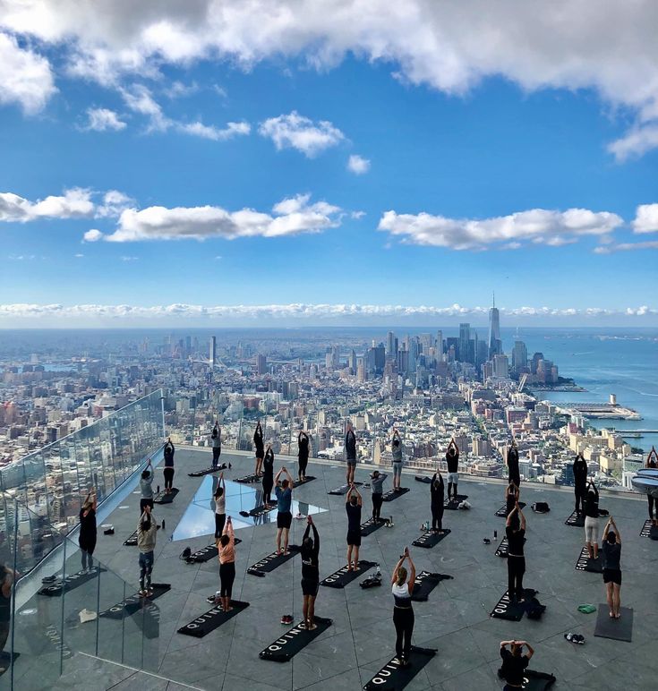 a group of people doing yoga on top of a building with the city in the background