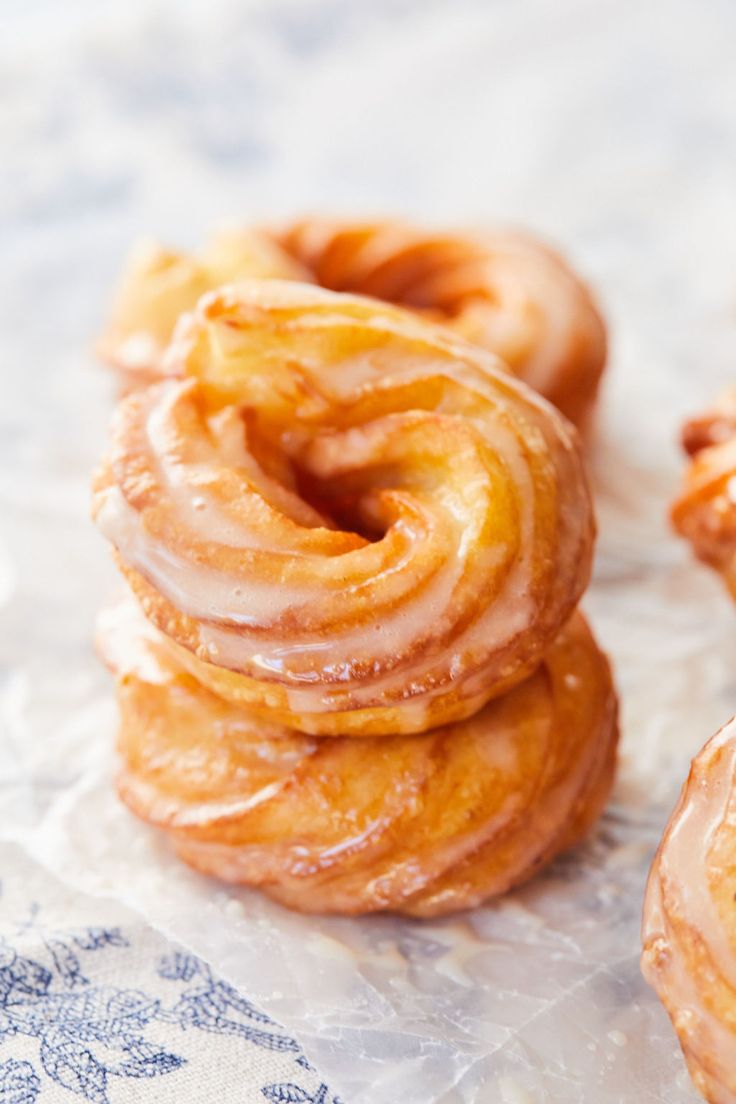 several glazed donuts stacked on top of each other in front of a blue and white tablecloth