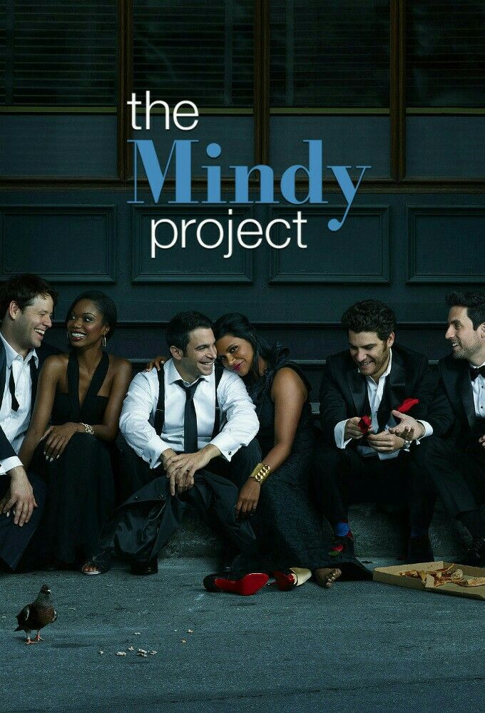 a group of people sitting on the ground in front of a sign that says the mindy project