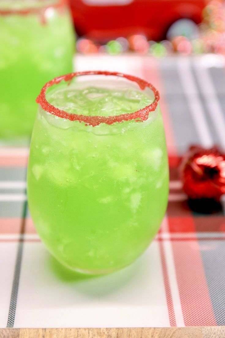 two glasses filled with green liquid sitting on top of a checkered tablecloth covered table