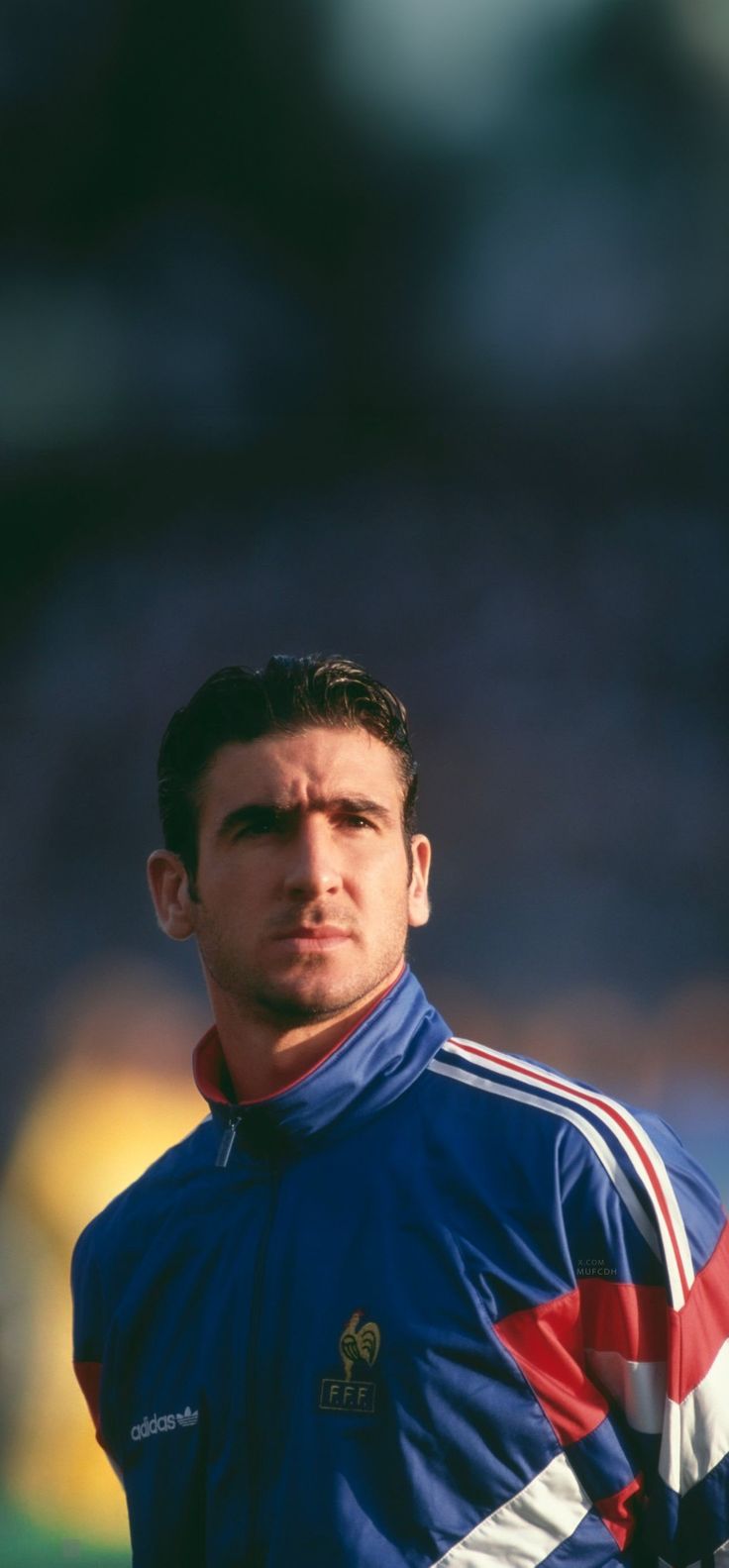 a man in a blue shirt standing on a soccer field