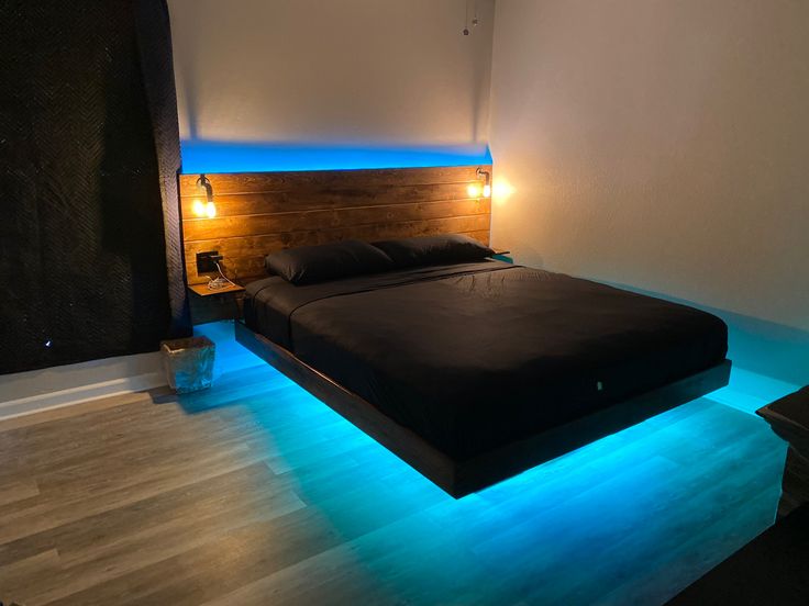 a bed that is sitting in the middle of a room with blue lights on it