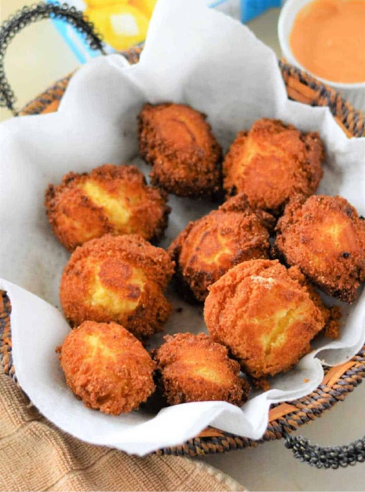 some fried food is in a bowl on a table with sauces and a napkin