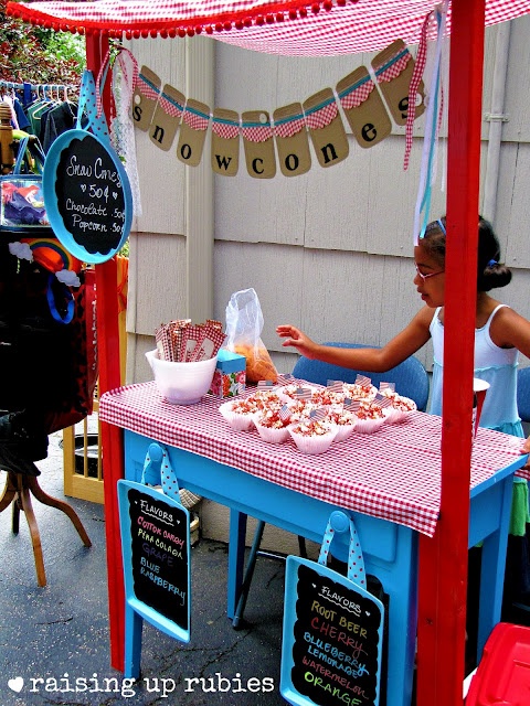 a woman sitting at a table with food on it and bunting flags hanging from the ceiling