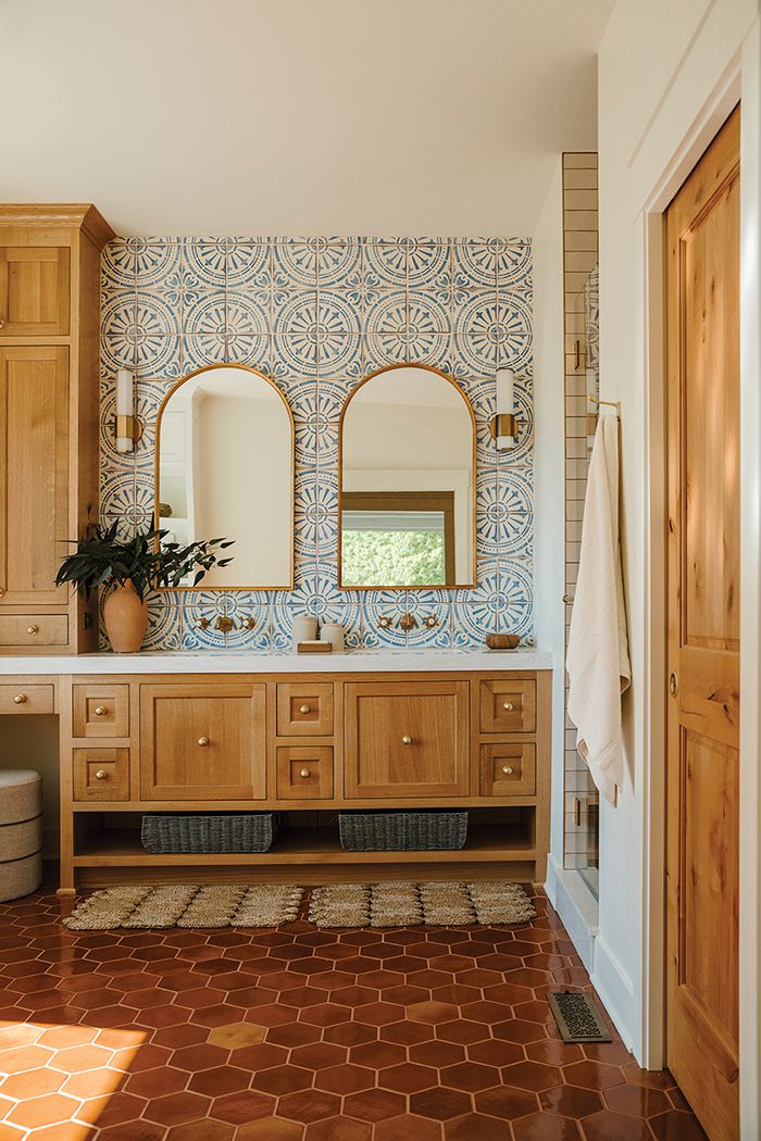 a bathroom with wooden cabinets and two mirrors on the wall next to a tub in front of a window