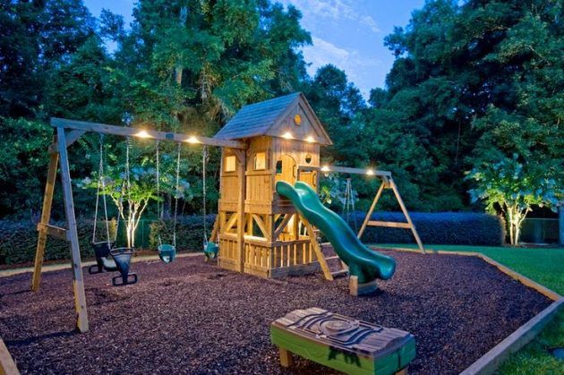 a wooden swing set in the middle of a park at night with lights on it