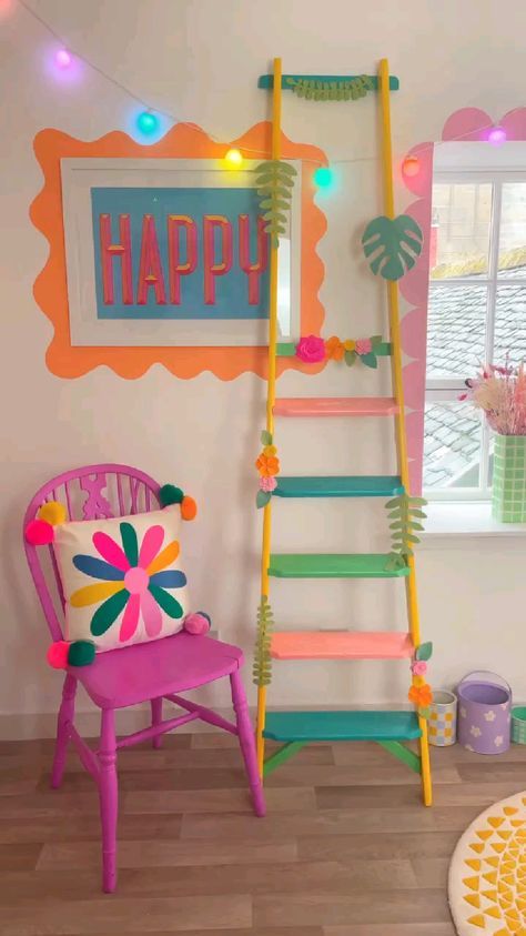 a room with a ladder, chair and wall hanging on the wall that says happy