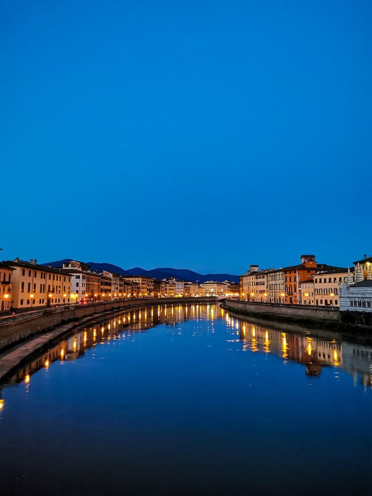 a river running through a city with buildings on both sides and lights reflecting in the water