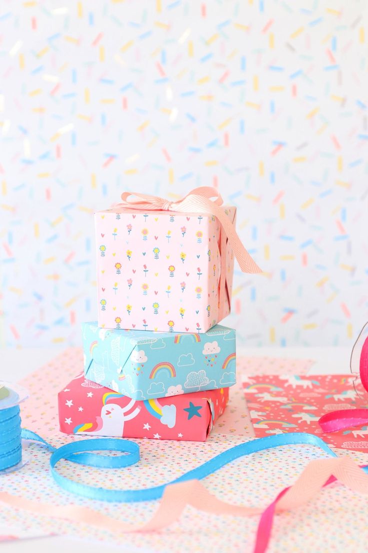 three boxes are stacked on top of each other with ribbons and confetti around them