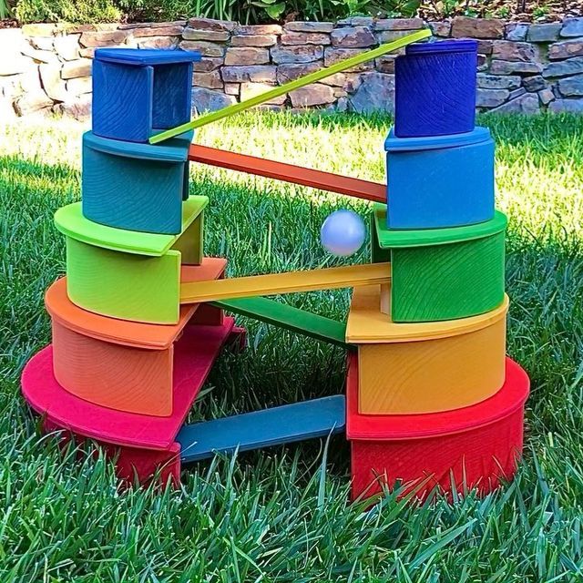 a multicolored wooden toy tower in the grass