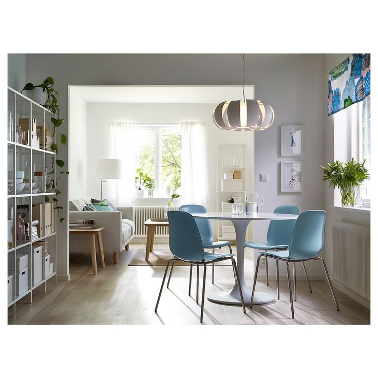 a dining room table with blue chairs next to a book shelf and bookshelf