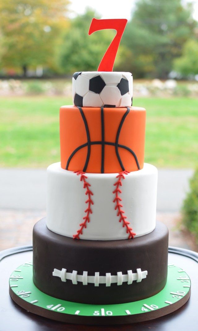 a three tiered cake with a basketball and soccer ball on top