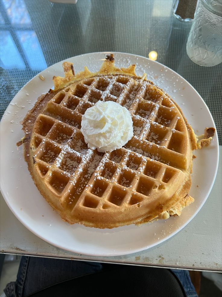 a waffle topped with whipped cream on a white plate