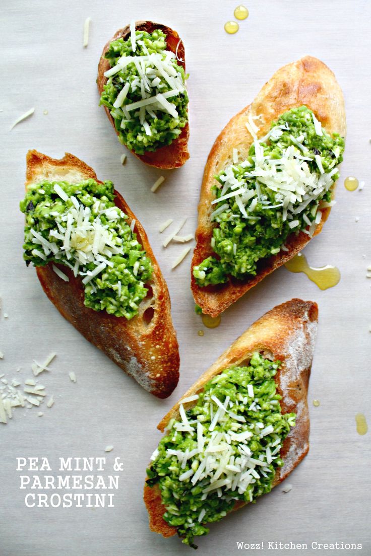 four pieces of bread with pesto and cheese on them sitting on a white surface