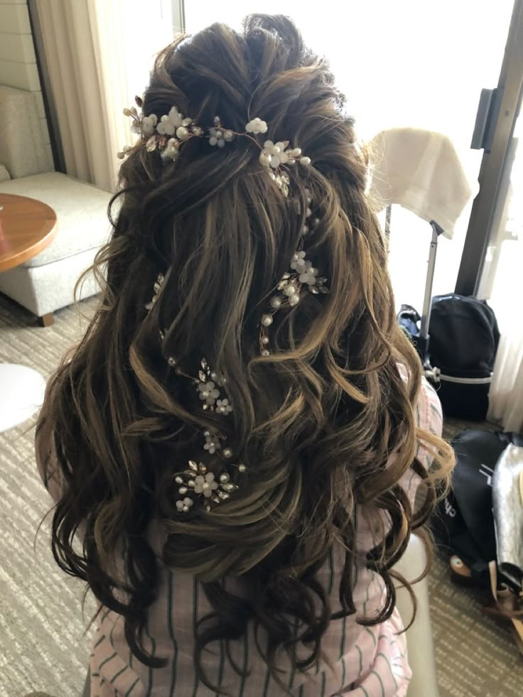 the back of a woman's head with flowers in her hair, sitting on a bed