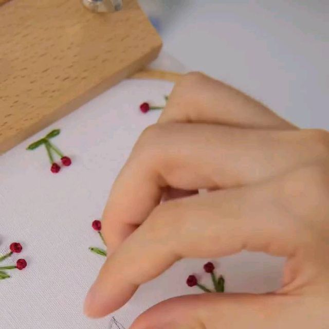 someone is stitching flowers on a piece of cloth