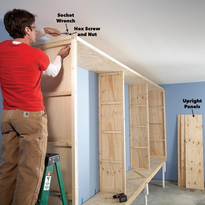 a man standing on top of a wooden shelf in a room with blue walls and flooring