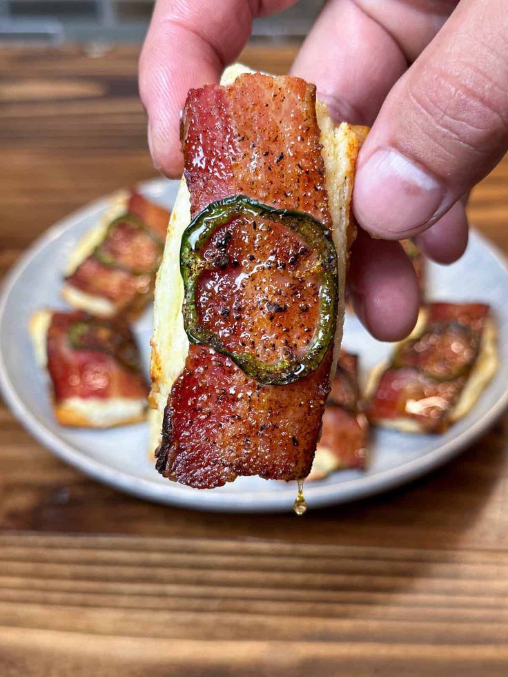 someone is holding up a piece of bacon wrapped in cheese and jalapenos