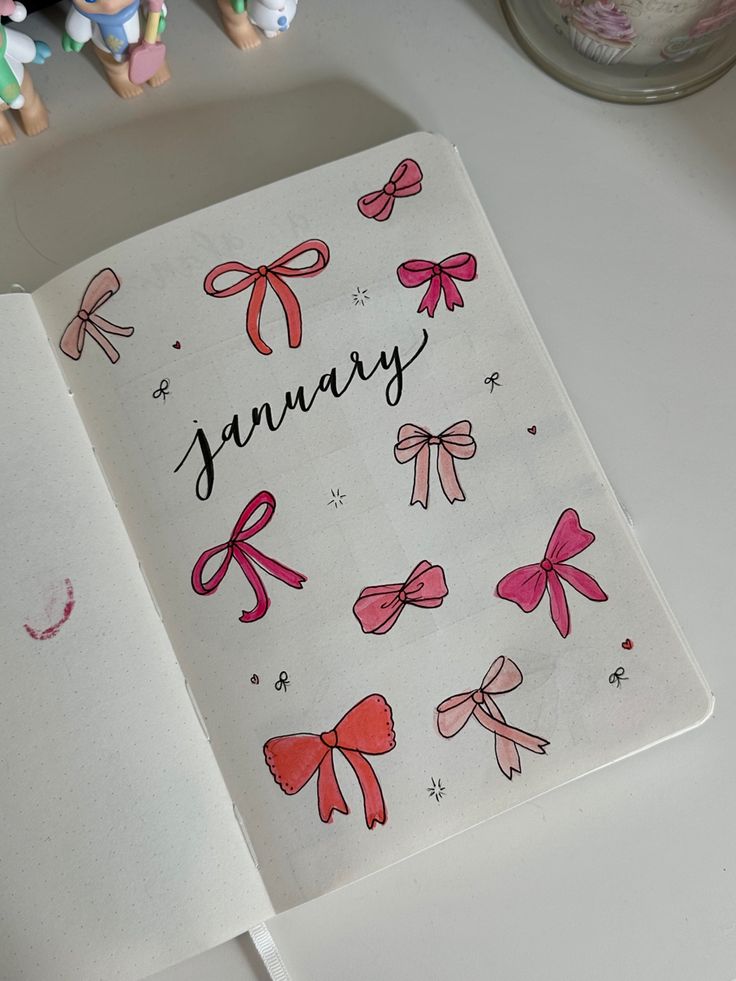 an open book with pink bows and the word january written on it next to small figurines