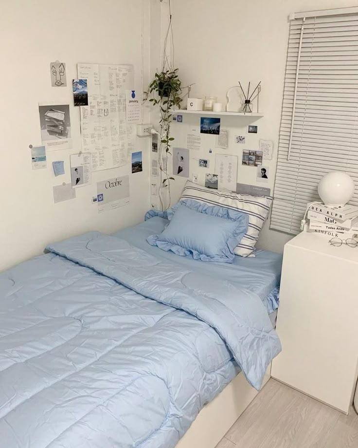 a bed with blue comforter and pillows in a room next to a white dresser