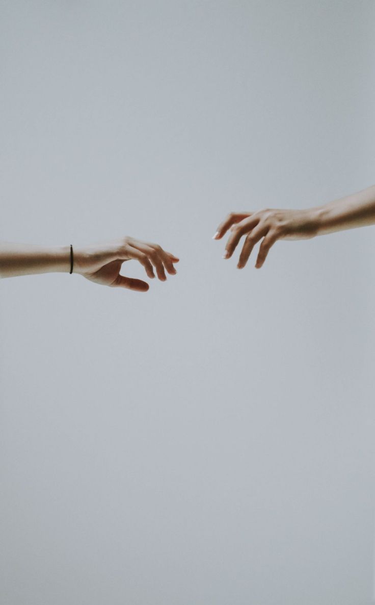 two hands reaching out towards each other with their arms extended in front of the camera