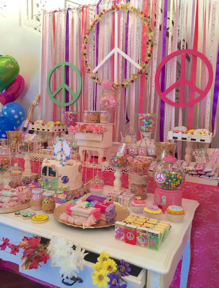 a table topped with lots of cakes and desserts next to colorful balloons in the background