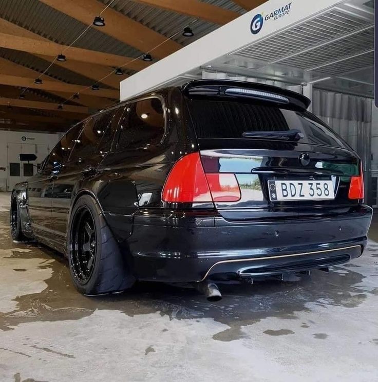 the back end of a black car parked in a garage