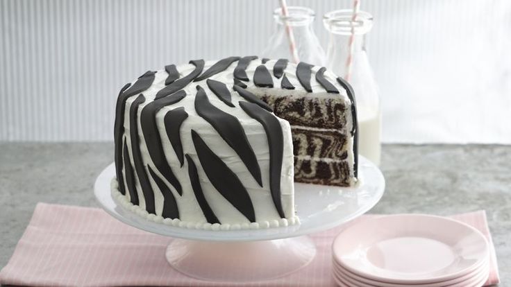 a zebra print cake sitting on top of a table next to plates and milk bottles