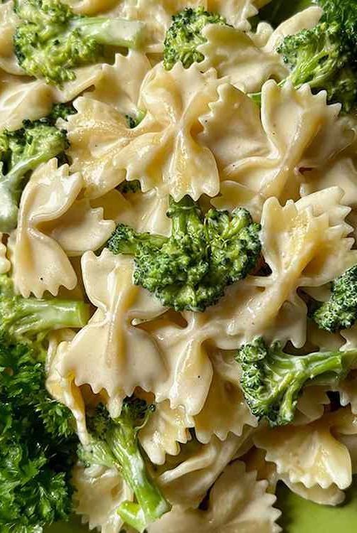 a green plate topped with pasta and broccoli