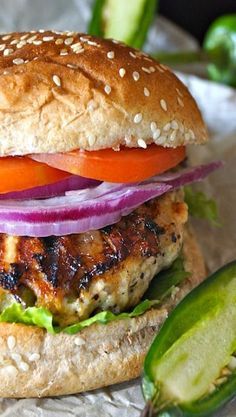 a chicken burger with lettuce, tomato and onion on a piece of tin foil