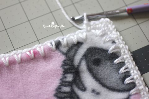 a close up of a crocheted animal on a piece of cloth next to a sewing needle