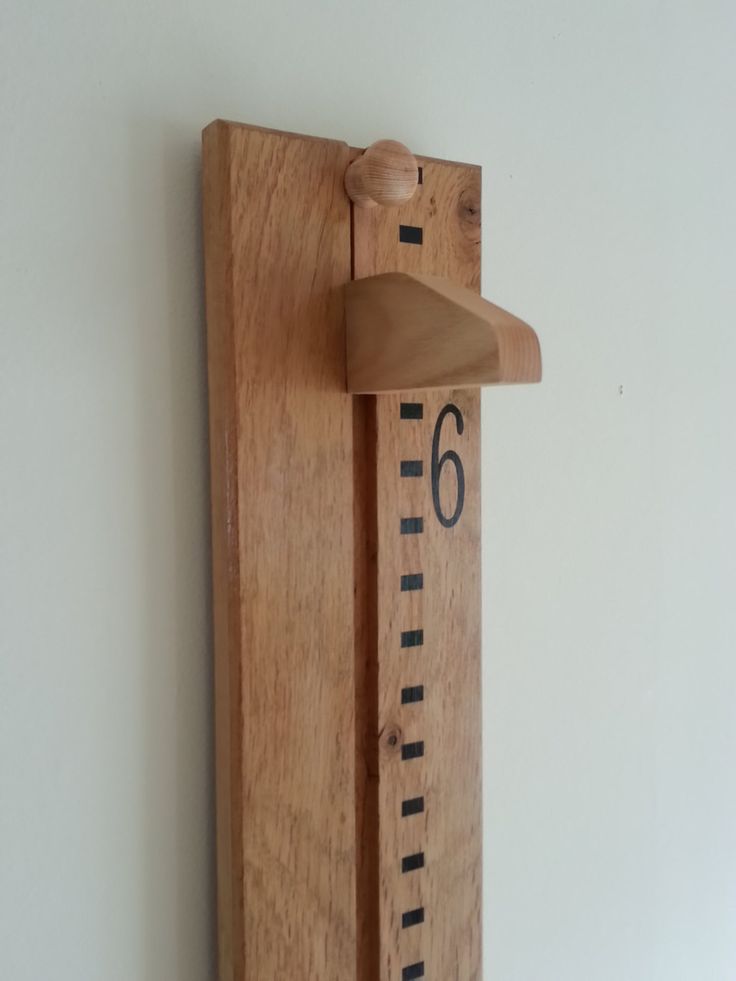 a wooden ruler mounted to the wall with a measuring tape on it's side