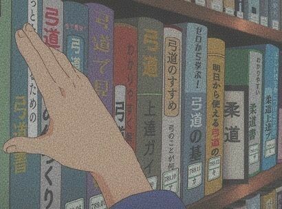 a hand reaching for books on a book shelf