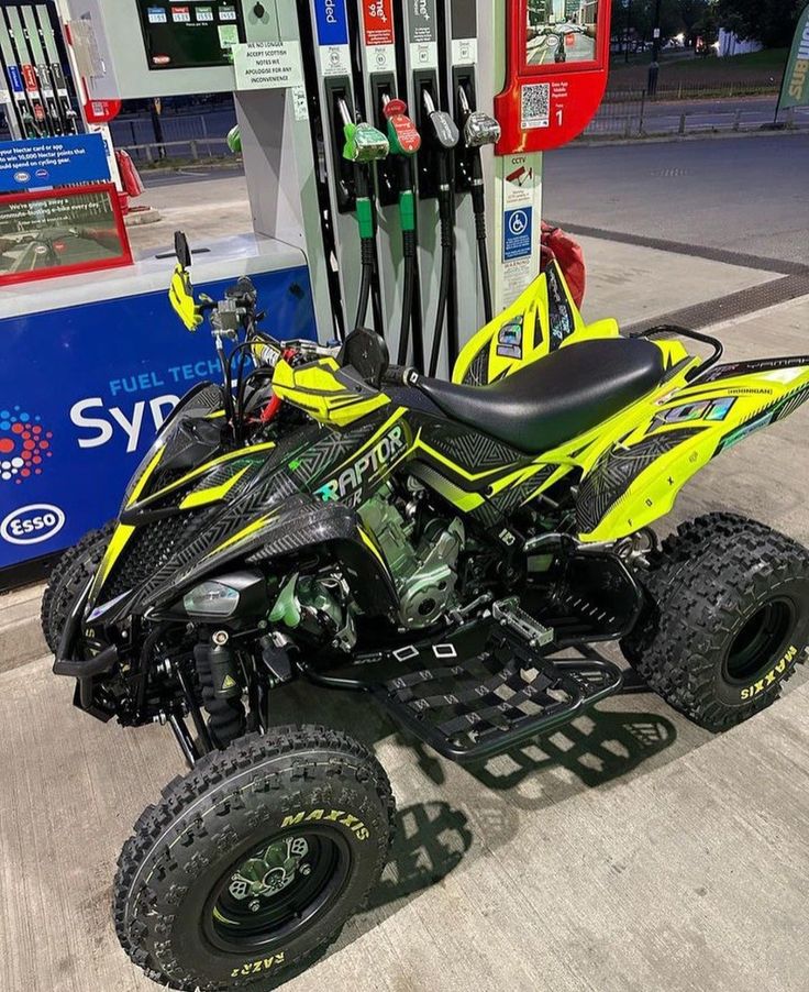 a yellow and black atv parked next to a gas pump