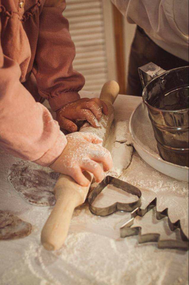 two people are making dough on a table with cookie cutters in front of them