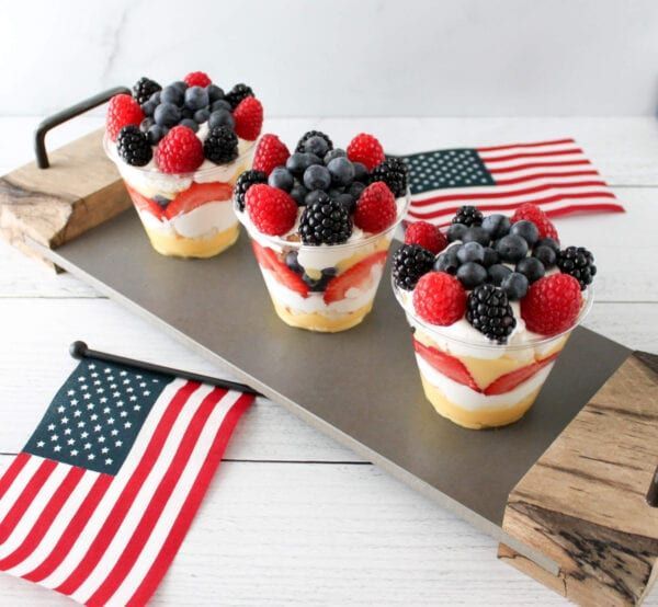 three cupcakes with berries, raspberries and blueberries on them sitting on a metal tray