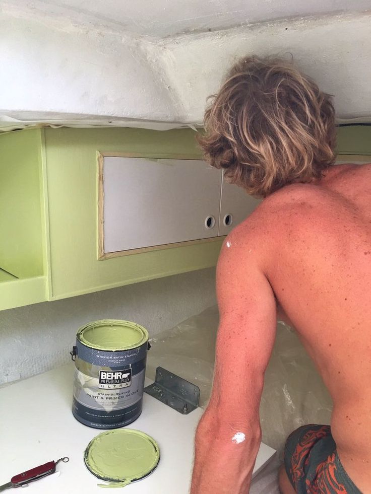 a man is painting the wall in his kitchen with green paint and some tools on the counter