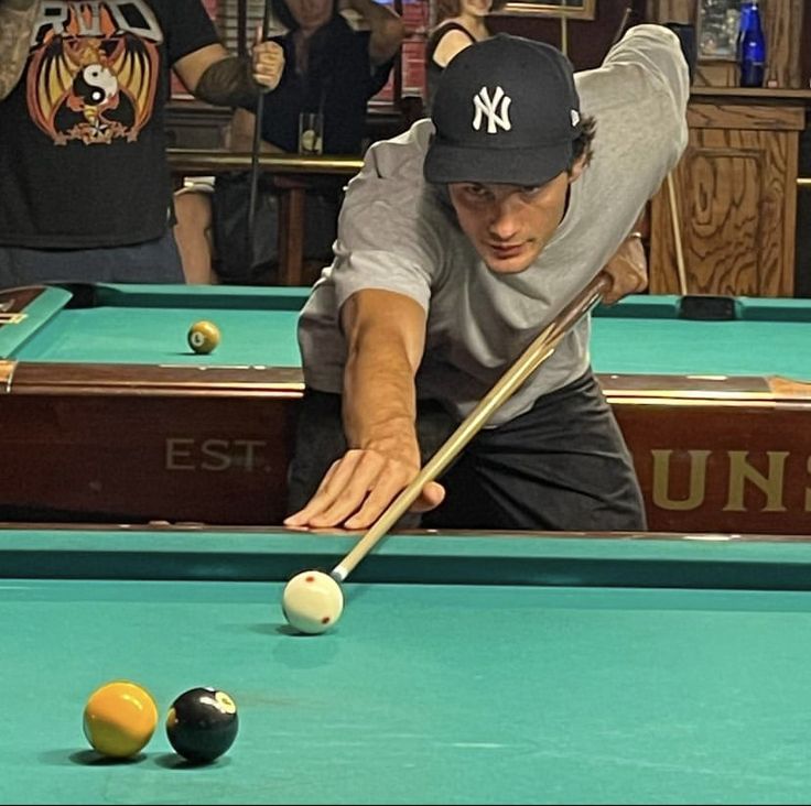 a man leaning over to hit a pool ball