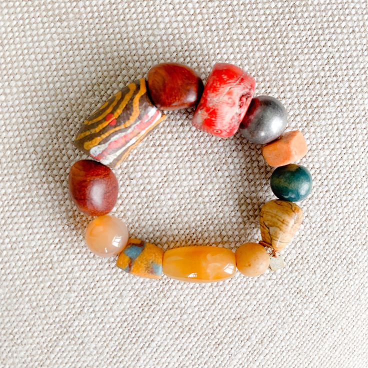 Pink, peach, yellow and greens all the bright colors of a coastal city. Features rosewood, peach jade, red coral, honey jade and jasper. African prayer beads from a weeding ceremony necklace. These prayer beads symbolize blessings, good health, happiness and long life. Comes in linen travel pouch. One of a kind. Made in USA. Bohemian Red Coral And Wooden Beads, Spiritual Multicolor Jade Bracelets, Multicolor Jade Spiritual Bracelets, Bohemian Orange Red Coral Beads, Orange Bohemian Red Coral Beads, Earthy Multicolor Beaded Bracelets With Natural Stones, Earthy Multicolor Beaded Bracelet With Natural Stones, Bohemian Orange Hand-strung Bracelet, Bohemian Orange Hand-strung Bracelets