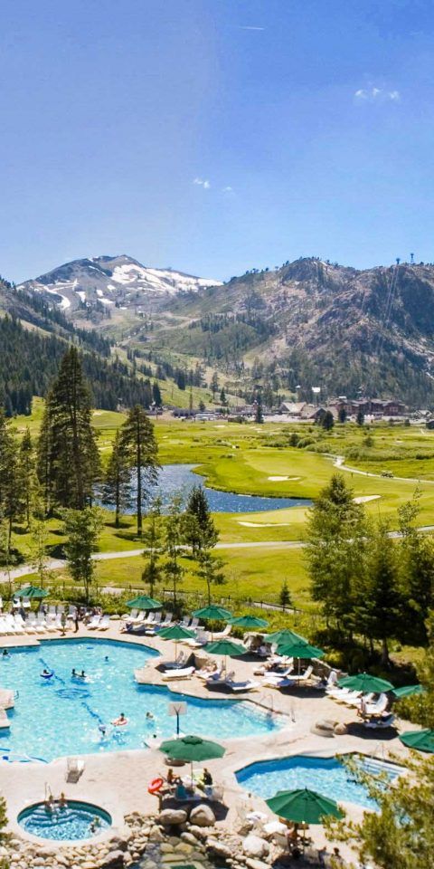 an outdoor swimming pool surrounded by trees and mountains