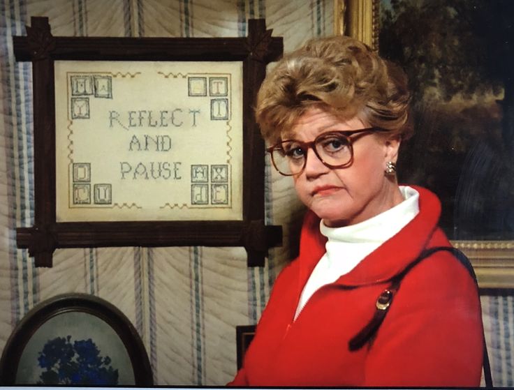 an older woman wearing glasses standing in front of a sign that says respect and pause