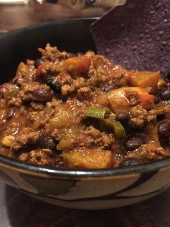 a bowl filled with chili and beans next to a purple tortilla chips on a table