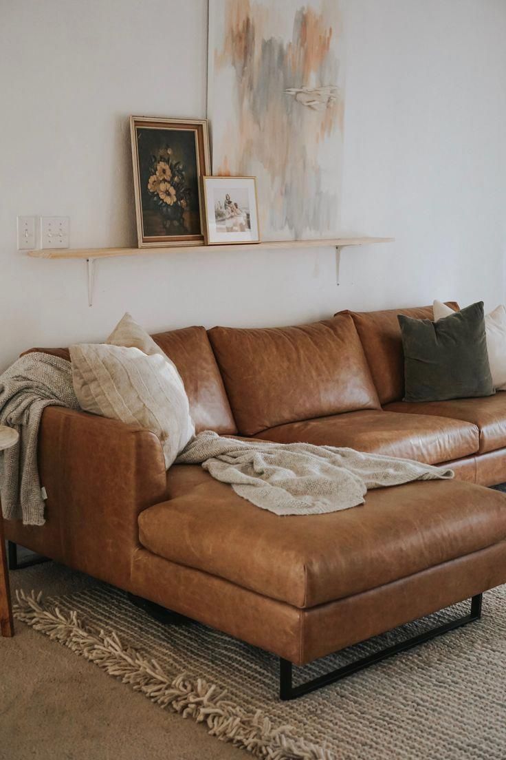 a living room with a couch, ottoman and pictures hanging on the wall above it